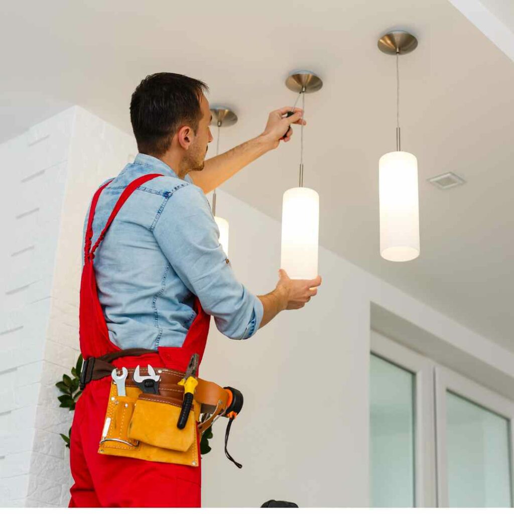 An emergency electrician hanging a light inside a house